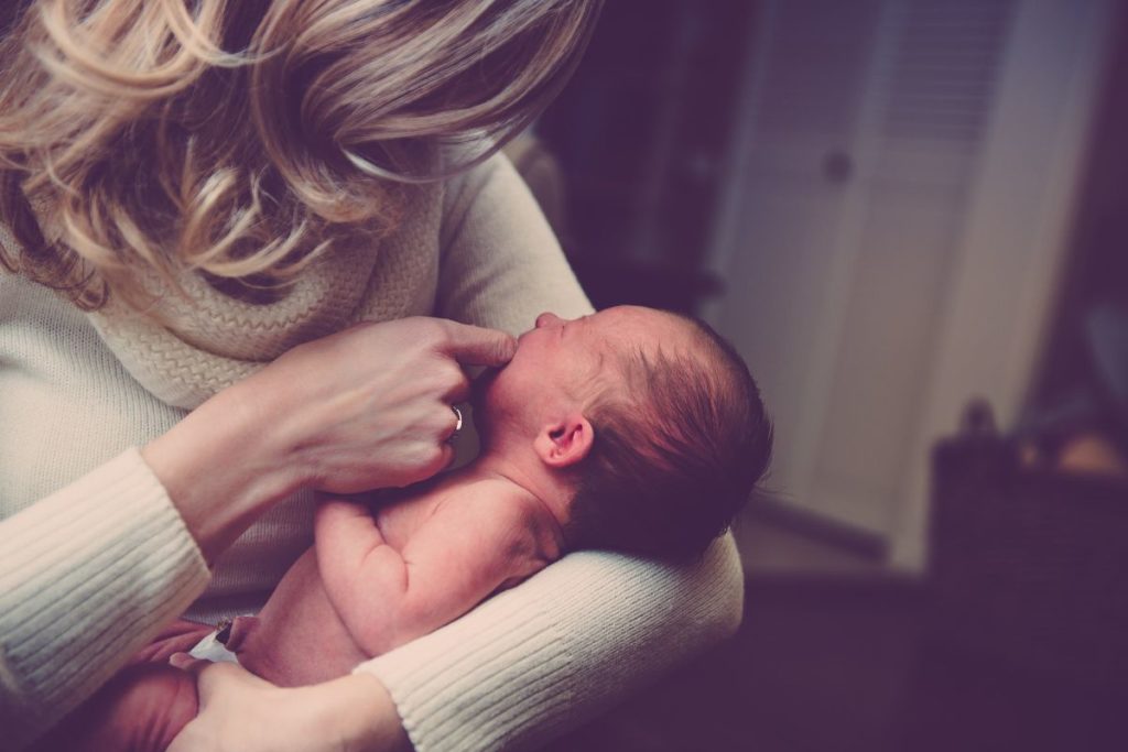 Newborn baby biting onto the mum's finger